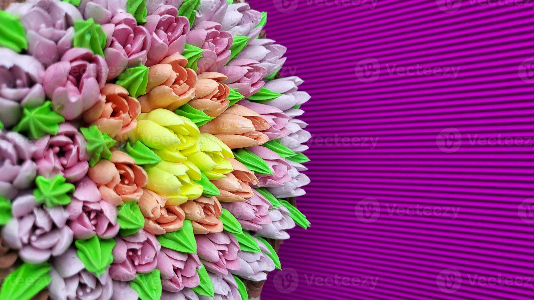 Multicolored cream tulips on a cake on a background of purple corrugated paper photo