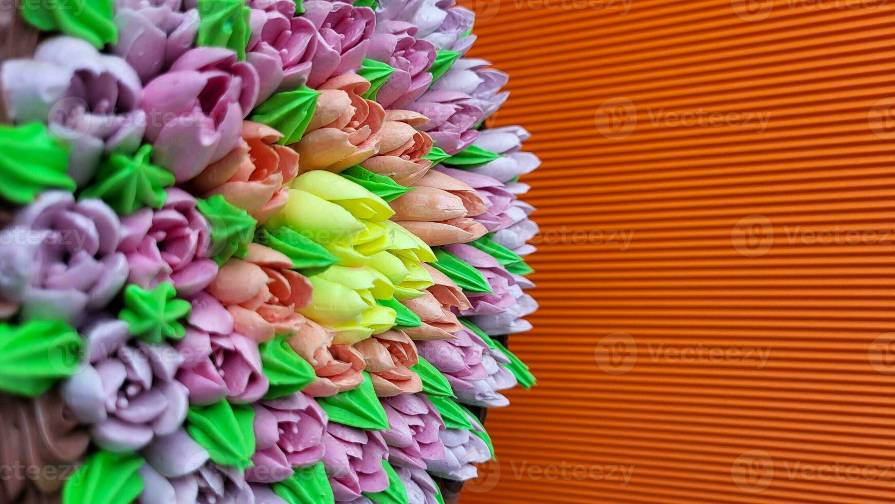 Multicolored cream tulips on a cake on a background of orange corrugated paper photo