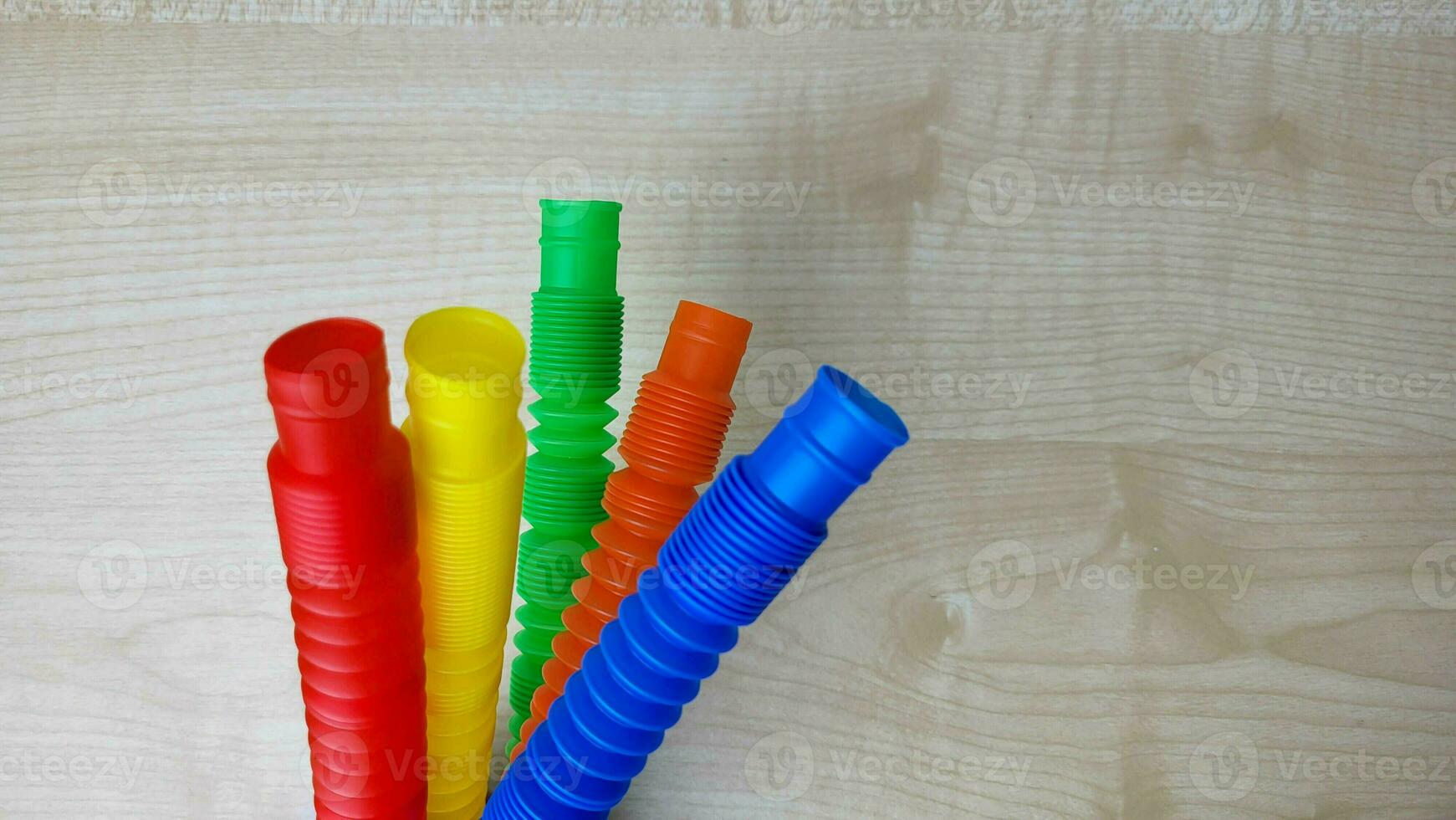 A set of funny plastic multicolored tubes-antistress on a wooden background photo