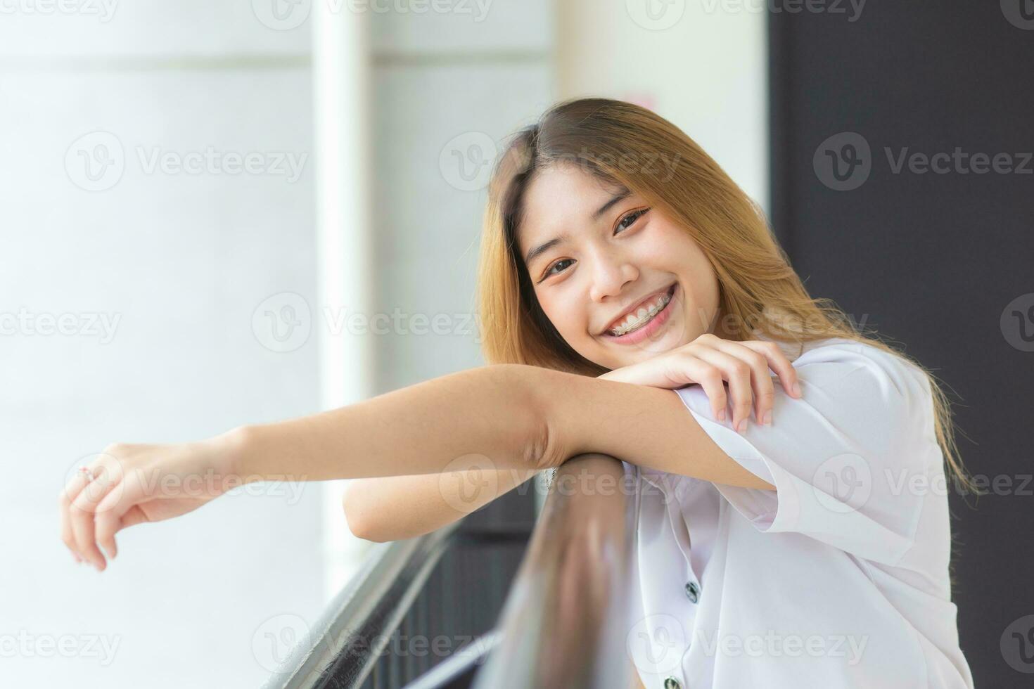 Young Asian cute student girl in Thai university student uniform smiling confidently and looking at camera in university background photo