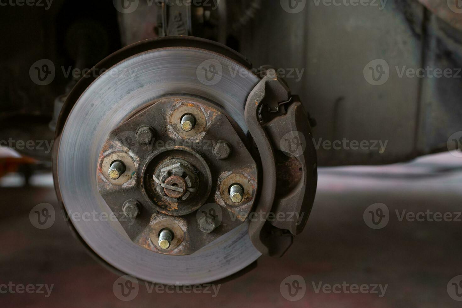 Brake discs, brake calipers and brake systems being maintained by a mechanic at a service center. Suspension of car for maintenance brakes and shock absorber systems. photo