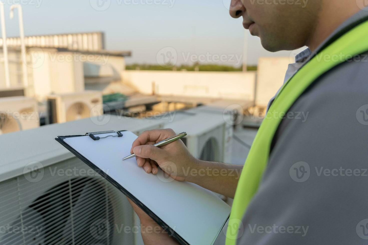 Asian maintenance engineer works on the roof of factory. contractor inspect compressor system and plans installation of air condition systems in construction. Checklist, inspector, control photo