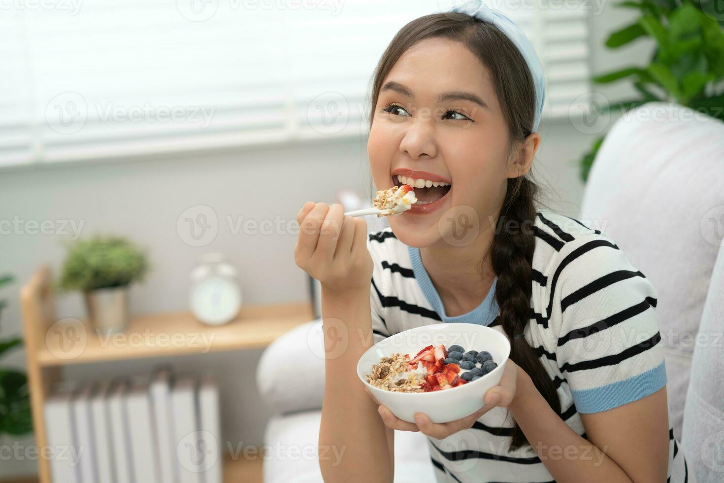 sano alimento. hermosa hembra niña disfrutar comer yogur, Granola, Fresco frutas en desayuno salud en casa. contento joven mujer sonrisa en Mañana bueno emoción. haciendo dieta, desintoxicación, dieta, limpiar comer, vegetariano foto