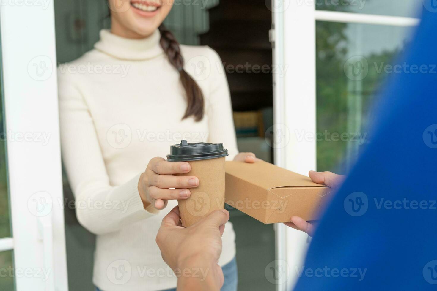 Happy smiling Asian woman receives paper box parcel of food from courier front house. Delivery man send deliver express. online shopping, paper container, takeaway, postman, delivery service, packages photo