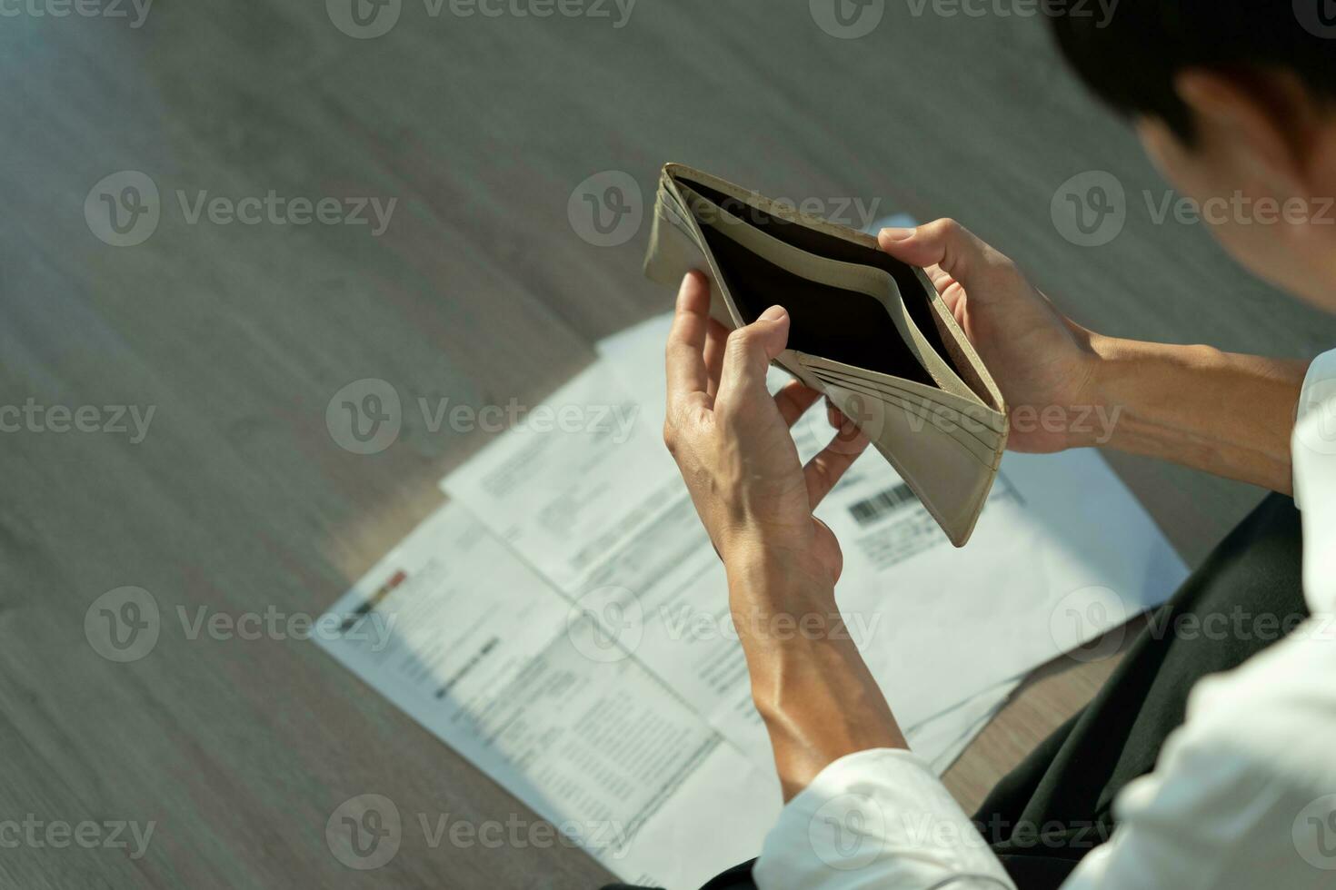 Stressed and headache asian man with large bills or invoices no money to pay to expenses and credit card debt. shortage, Financial problems, mortgage, loan, bankruptcy, bankrupt, poor, empty wallet photo