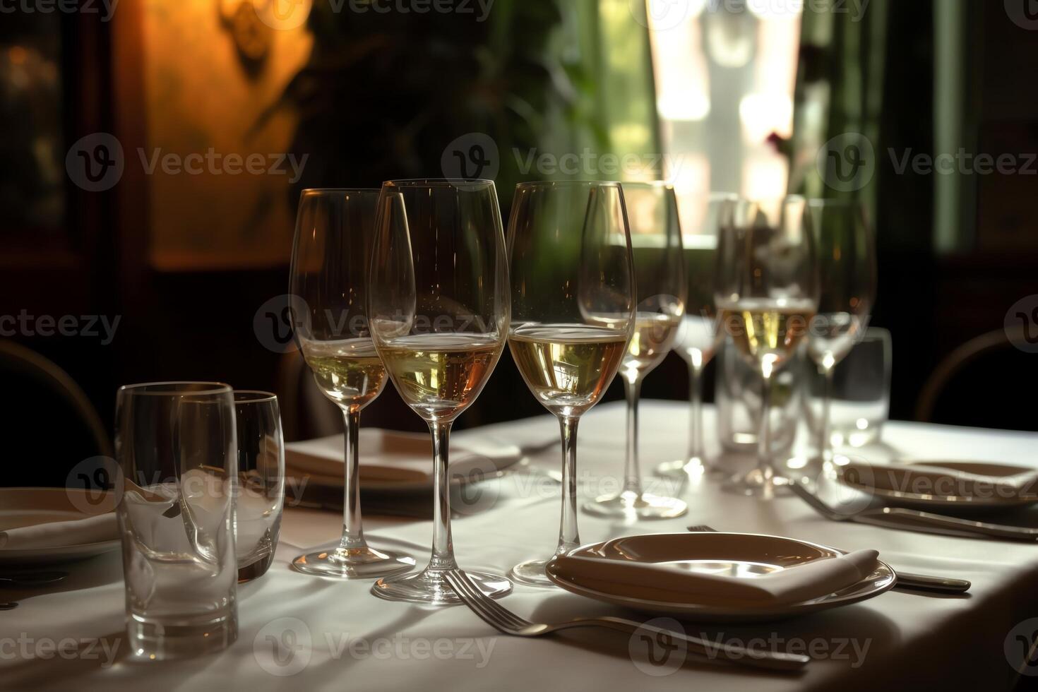 A table in a restaurant has glasses of champagne or white wine arranged on it. photo
