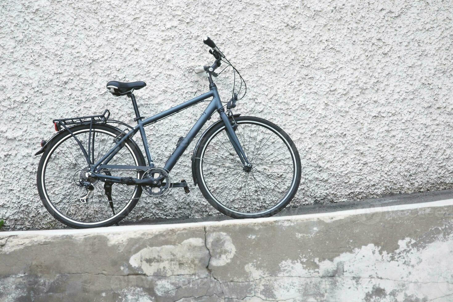 Bicycle parked by the wall outdoors photo