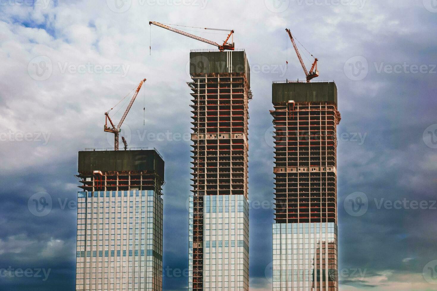 skyscrapers under construction, modern city buildings against dark stormy sky photo
