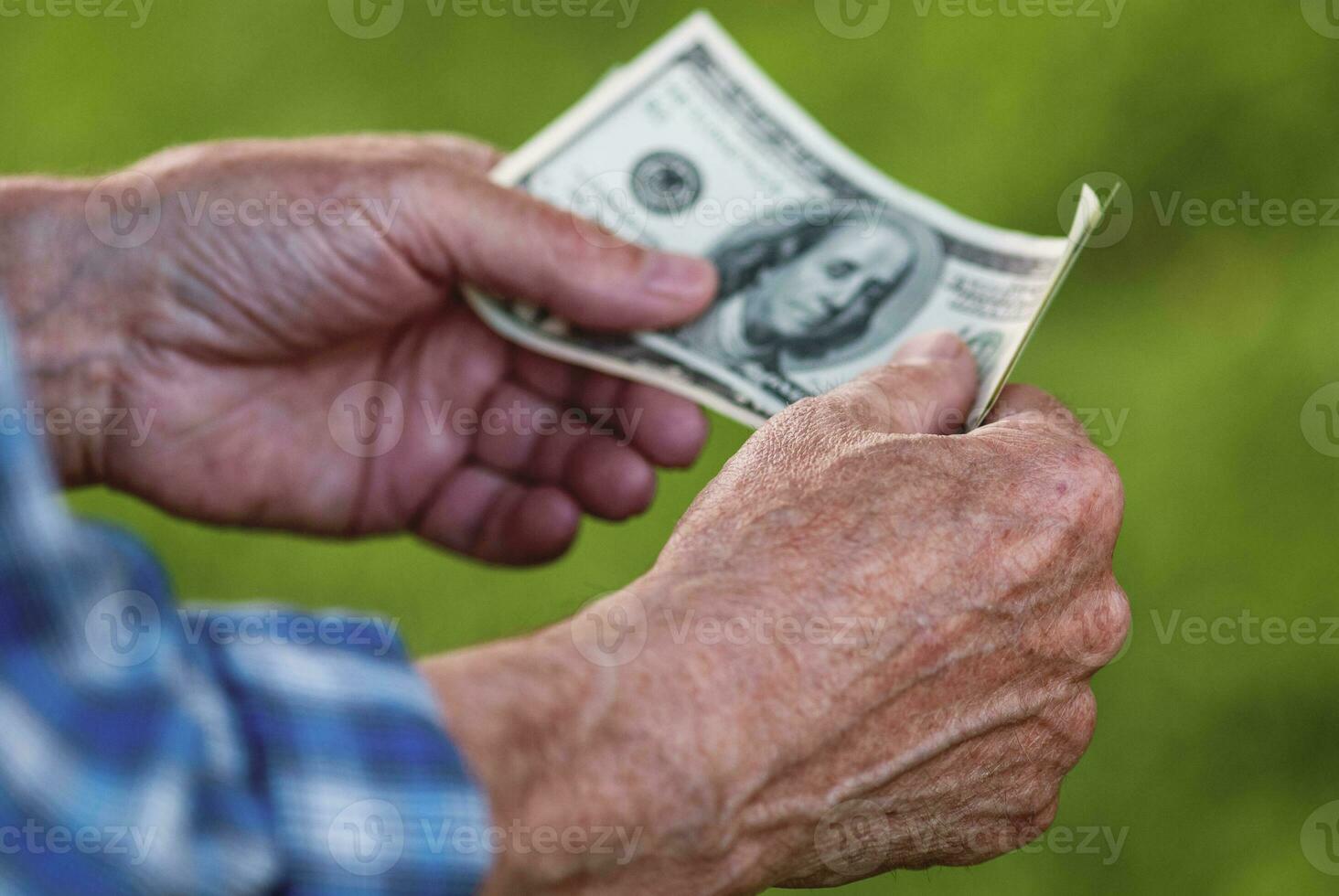 Senior man holding dollar banknotes, closeup of elderly male hands with hundred dollar bills photo