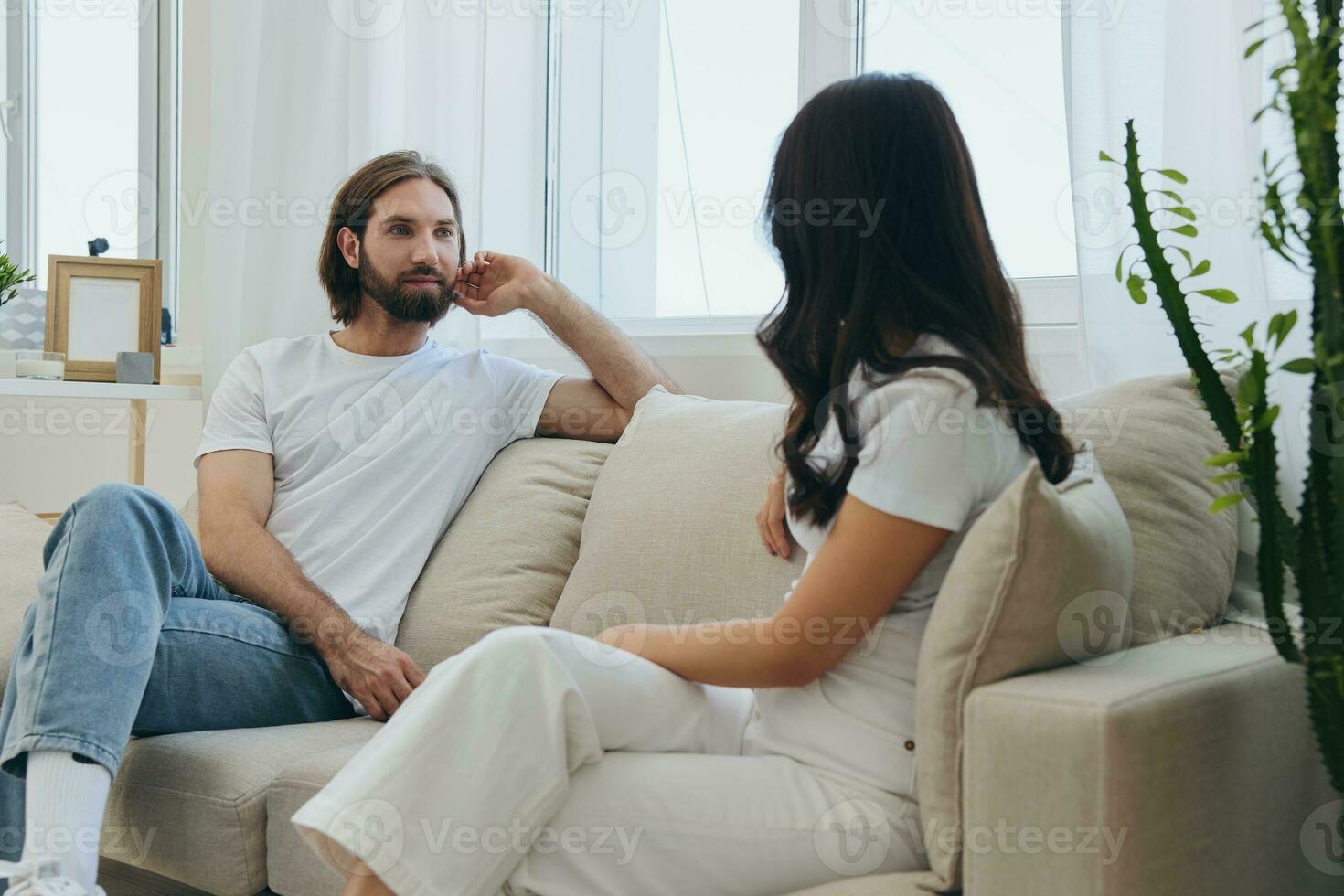 Man and woman friends sitting on the couch and smiling merrily talking to each other having a good time together. Lifestyle in happiness at home photo