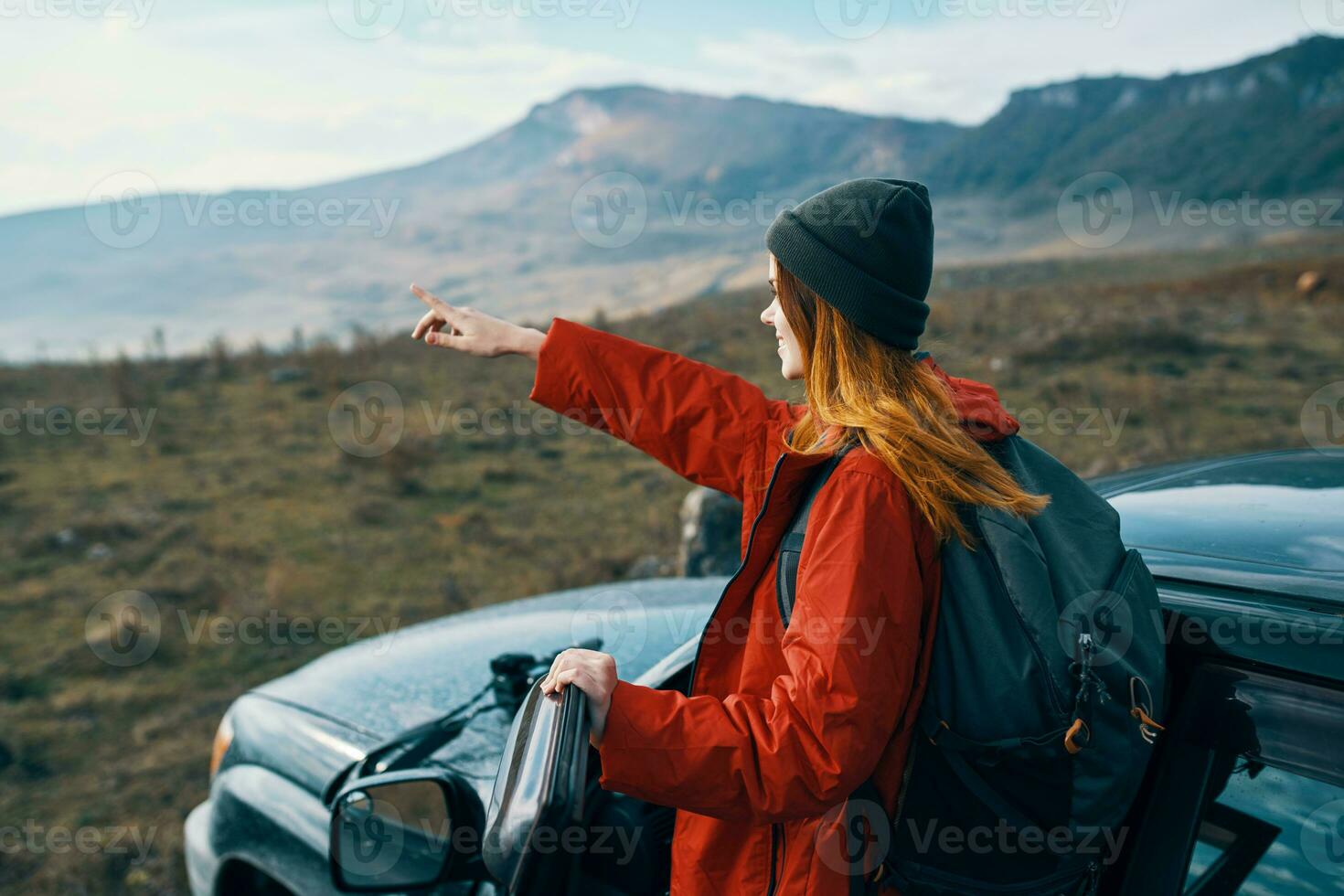 woman hiker in the mountains on nature near the car with a backpack on the back photo