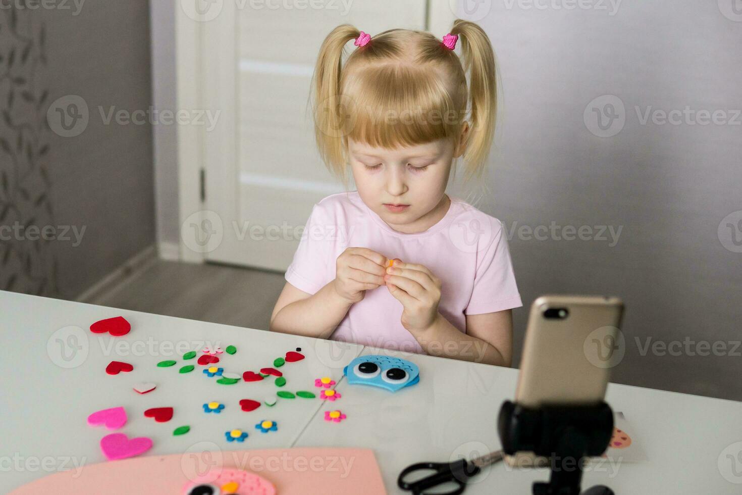 A blogger girl makes a felt craft for Valentine's Day in the shape of a heart. The concept of children's creativity and handmade. photo