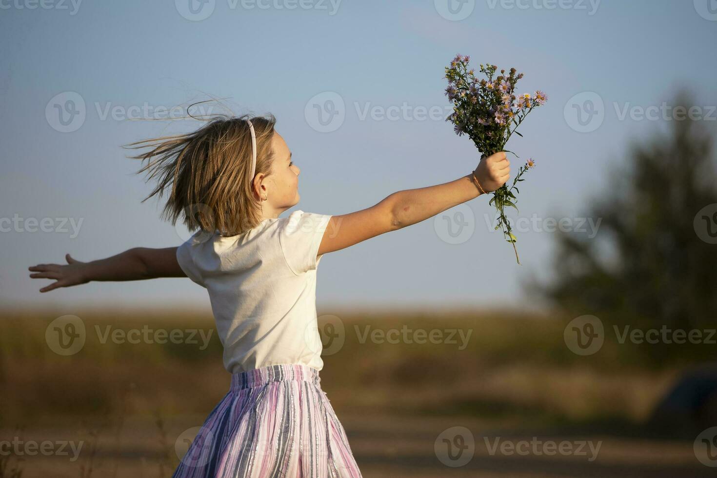 hermosa pequeño niña en el prado con un ramo de flores de flores un niño en un hermosa verano campo. foto