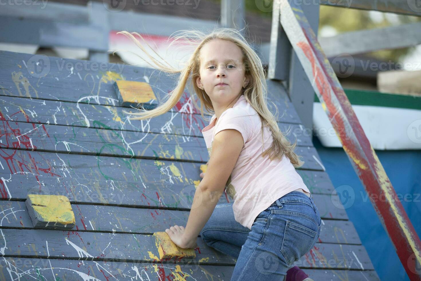 A little girl is climbing a rock climbing wall. The child plays on the children's slide. photo