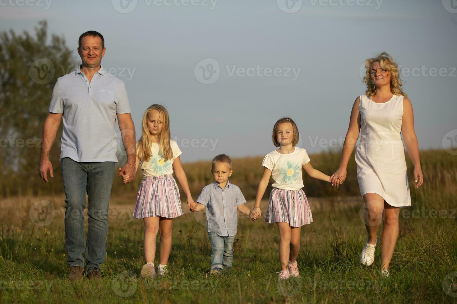 contento familia madre, padre, niños, hijo y hijas en naturaleza a puesta de sol. padres y niños son caminando juntos. el grande familia. foto