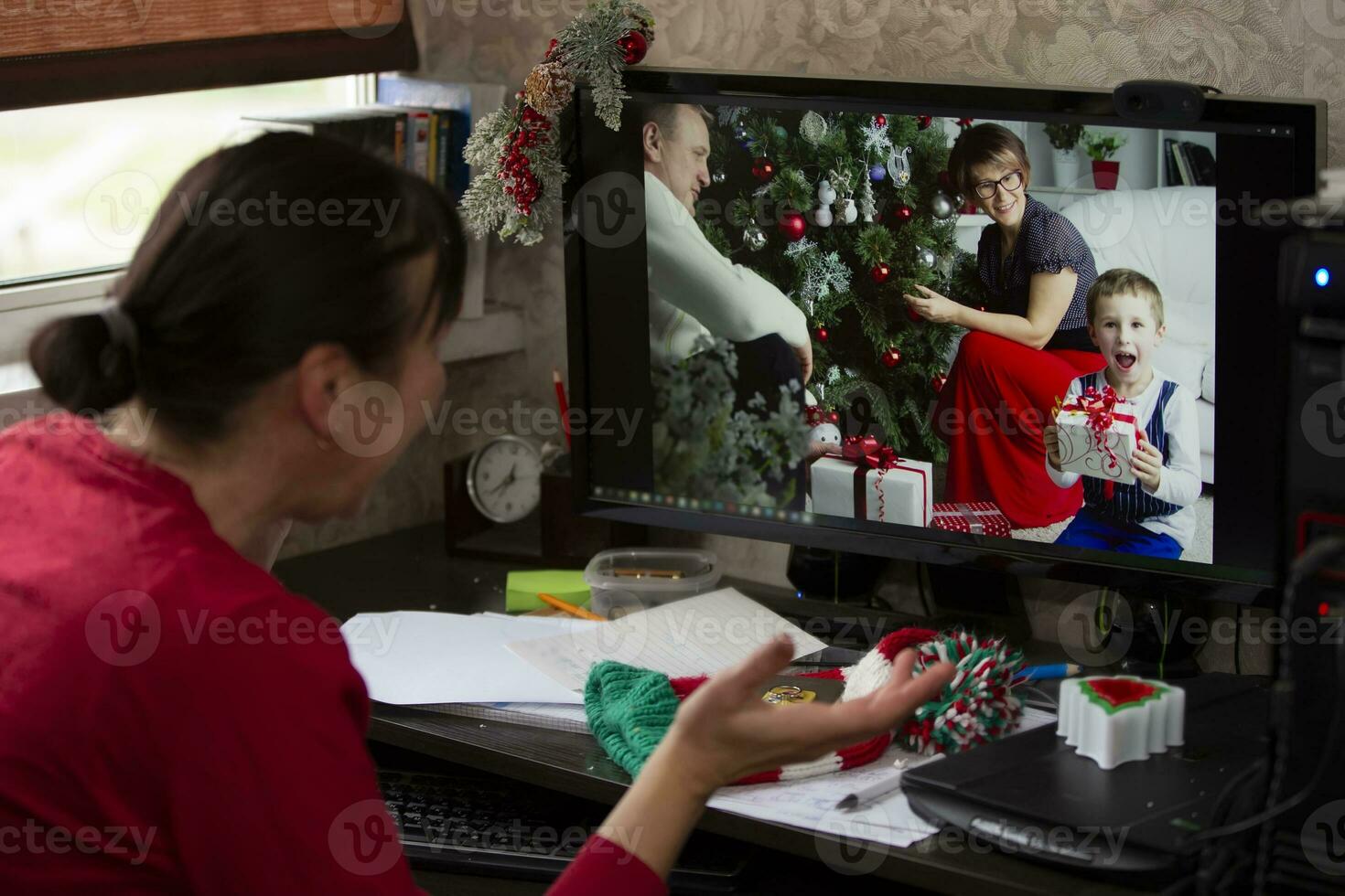A woman is sitting at a table and talking via video link with relatives at the holiday. Staying at home, quarantine and social distancing during the New Years. photo