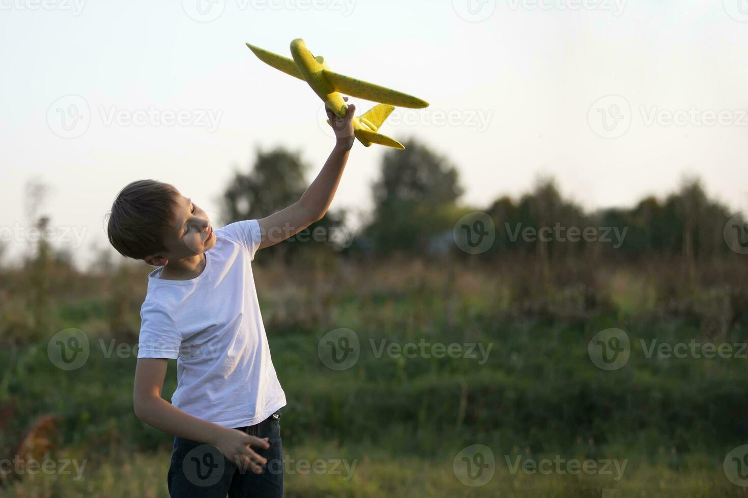 Little boy in the field plays with a yellow plane. photo