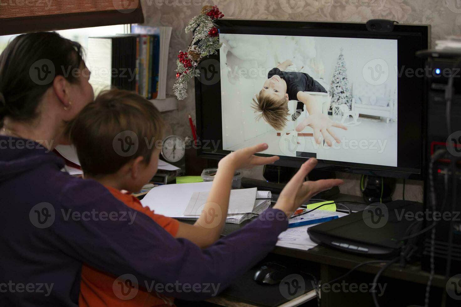 un mujer y un niño son sentado a un mesa y hablando vía vídeo enlace con un chico relativo o amigo. quedarse a hogar, cuarentena y social distanciamiento durante el nuevo años. foto