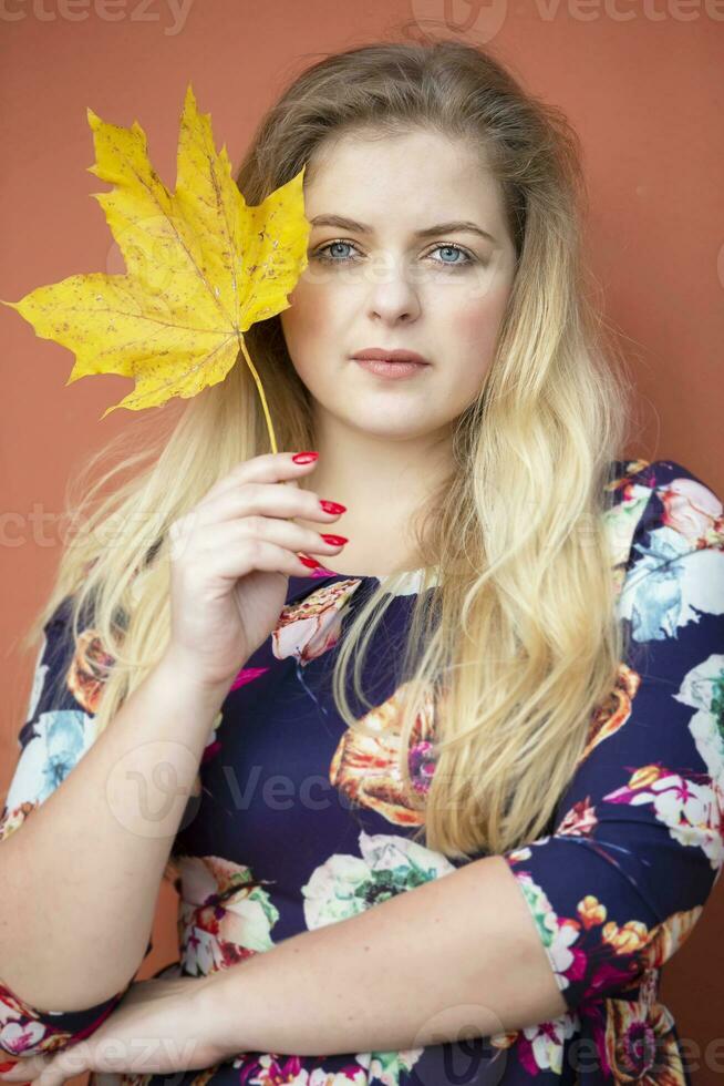 A beautiful blonde girl with blue eyes is holding a maple leaf. photo