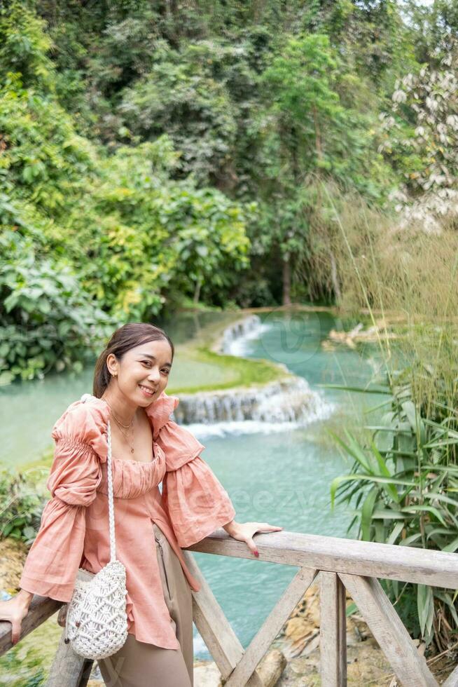 asiático mujer en pie en el de madera pasarela en el Kuang si cascada pulmón prabang, Laos foto