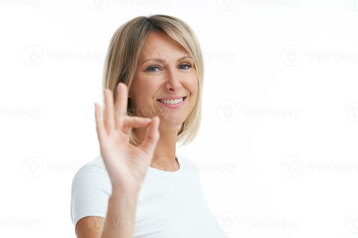 Picture of blonde woman over back isolated background showing ok photo