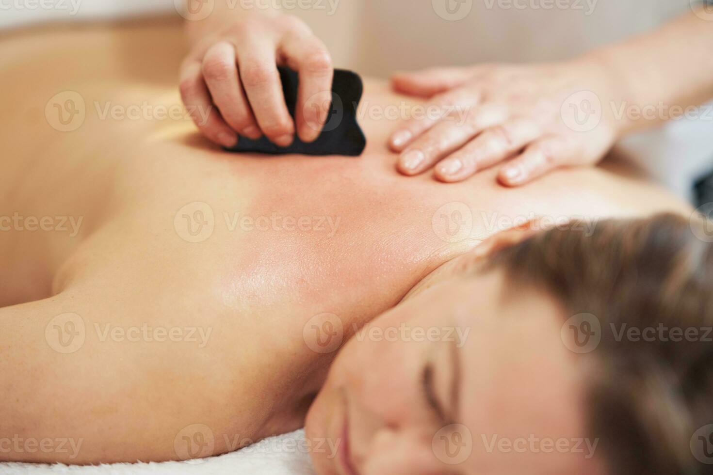 Woman having a gua sha massage in salon photo