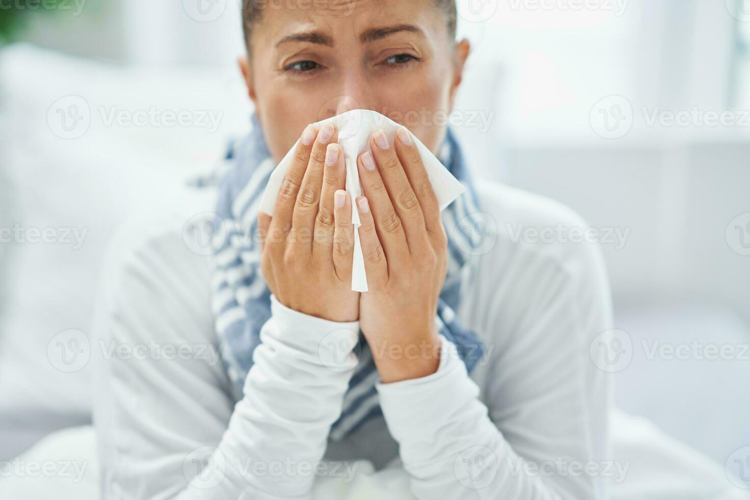 Young brunet woman sick in the bed with tissue photo