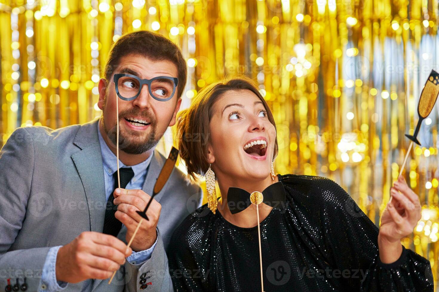 Couple over gold with photo booth accessories on party