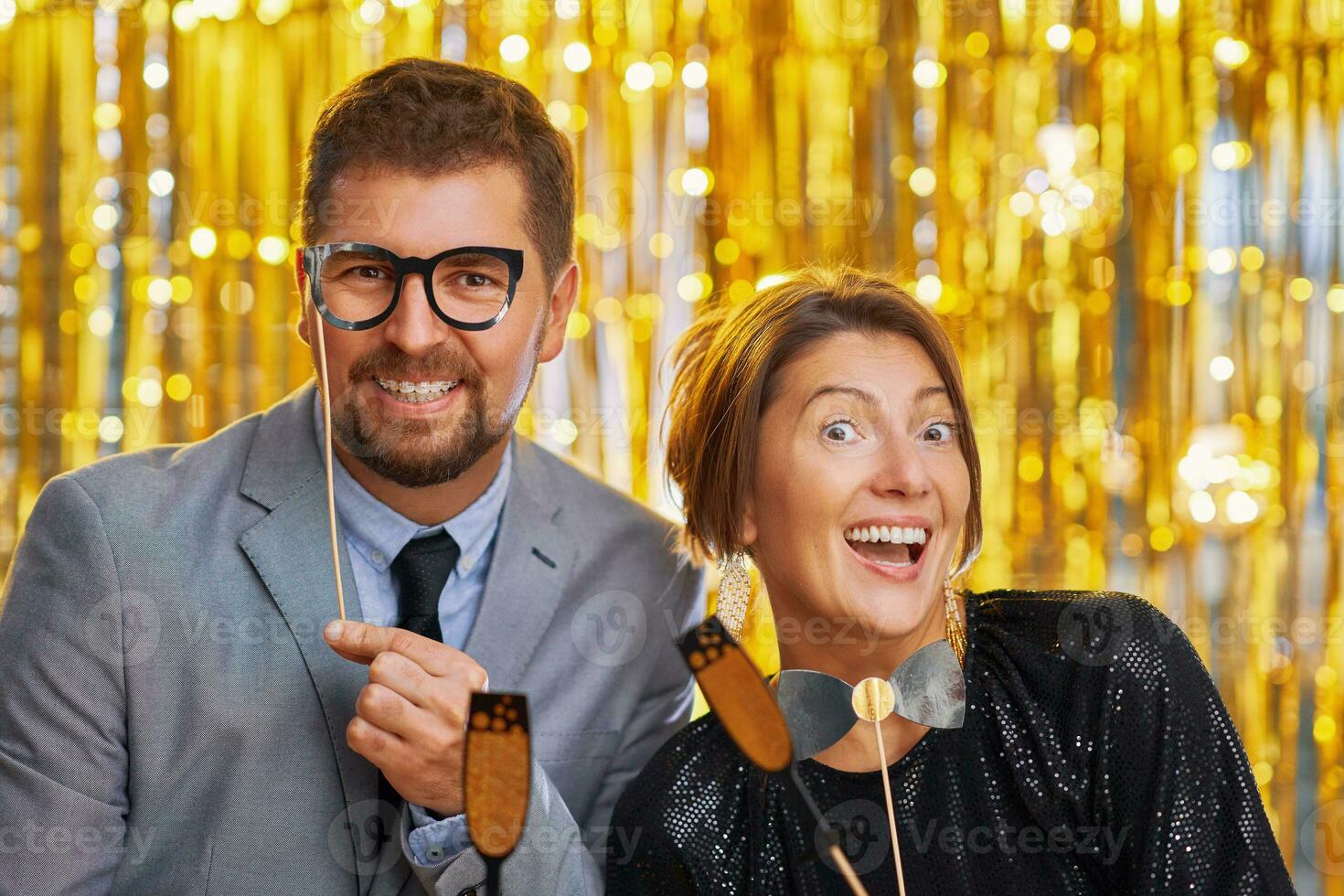 Couple over gold with photo booth accessories on party