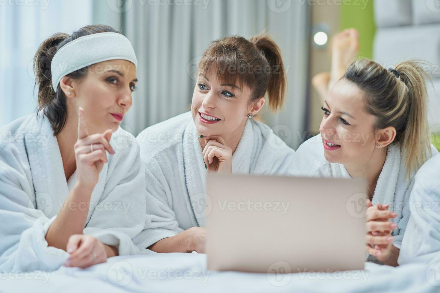 Group of girl friends at hotel spa party with laptop photo