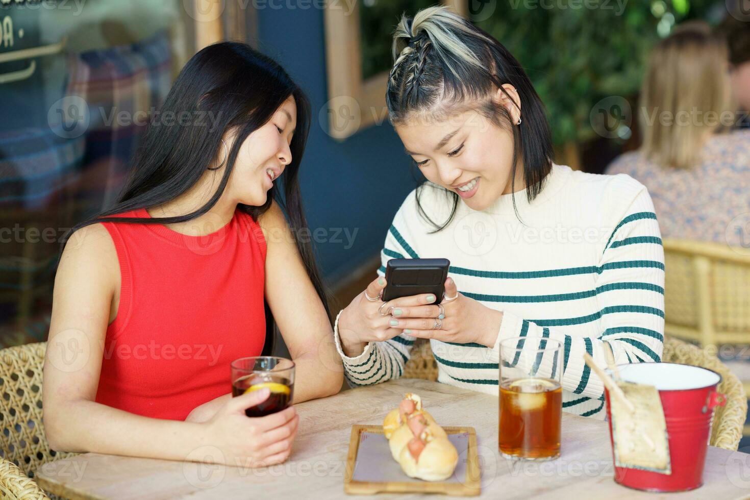 Positive Asian women taking picture of yummy food in cafe photo