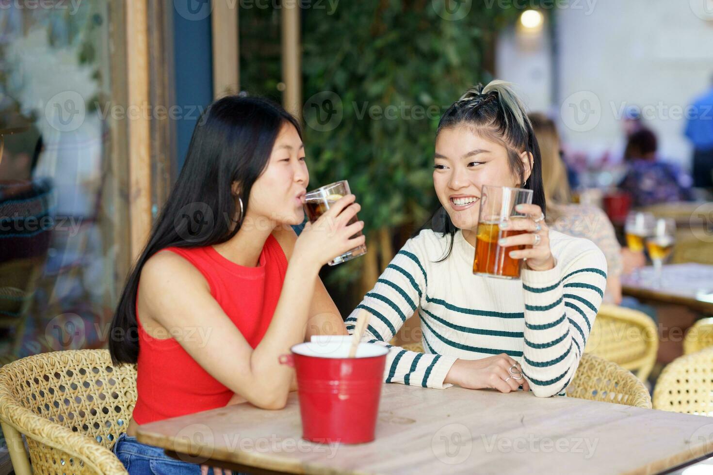 Smiling Asian friends drinking fresh beverages in cafe photo