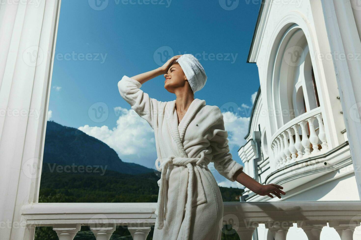 Woman in a white robe with a towel on her head on the balcony of the hotel architecture photo