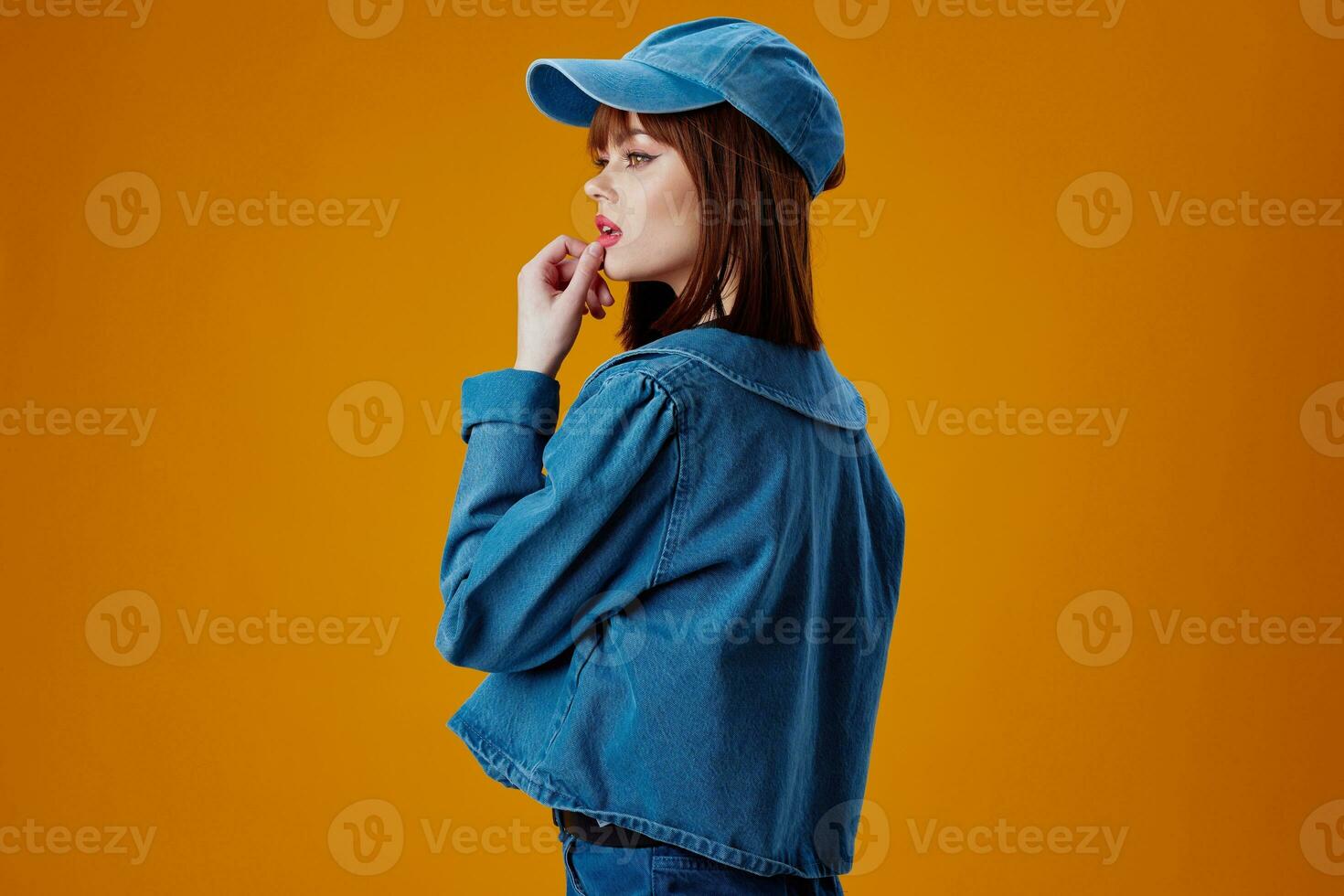 Portrait of a charming lady in a cap and denim jacket posing color background unaltered photo