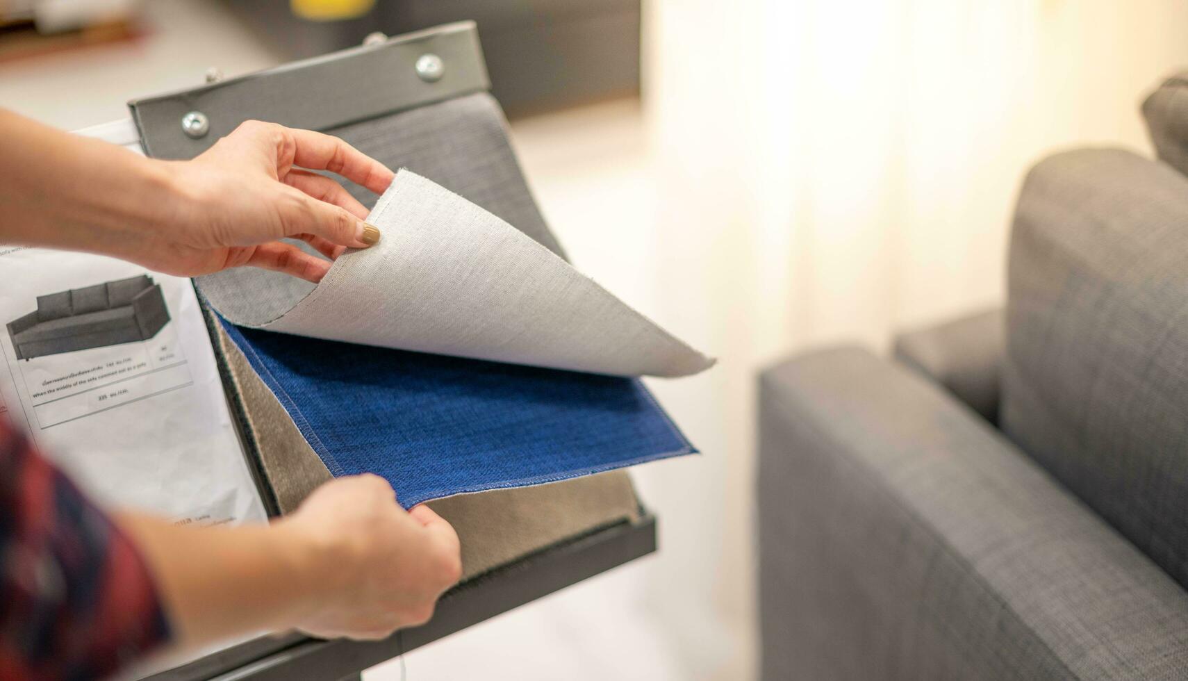 Female hand selecting the satin of cover sofa at the interior and furniture store. photo