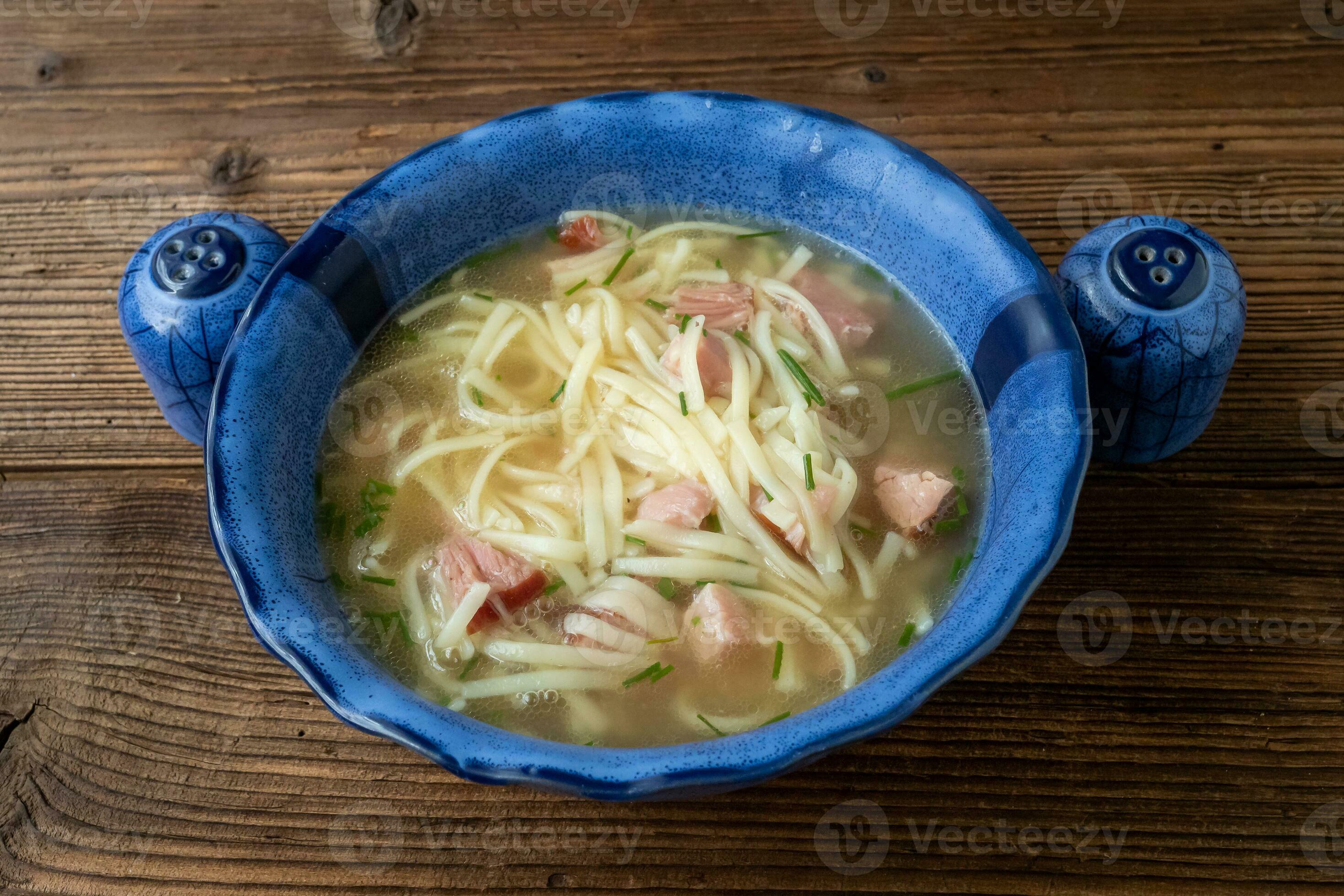 Meat broth soup with noodles in a blue bowl. Serving soup for lunch