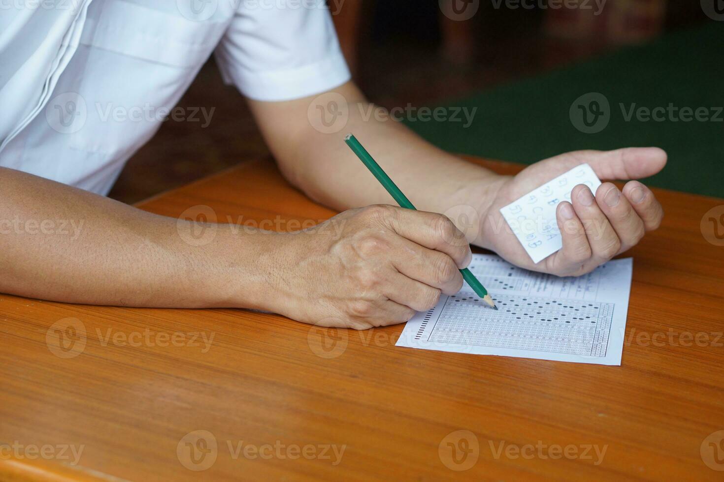 Closeup student doing examination, use pencil to write on paper and look at answers on another hand to cheat the test.  Concept, Dishonest behaviour. Education assessment. photo