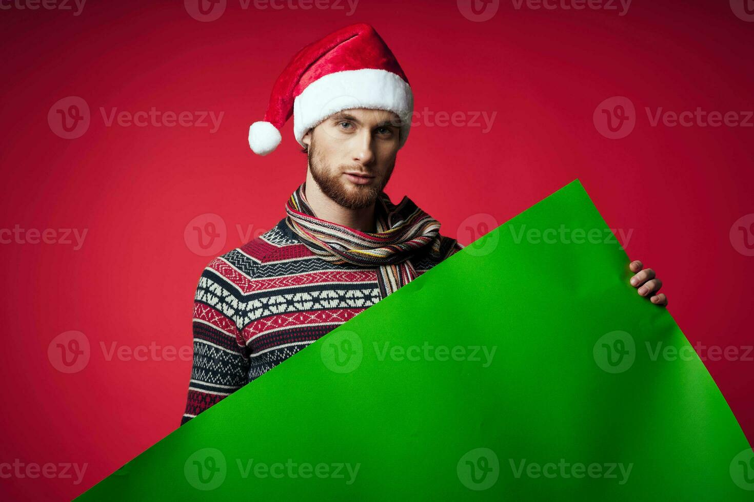 Cheerful man in a santa hat holding a banner holiday red background photo