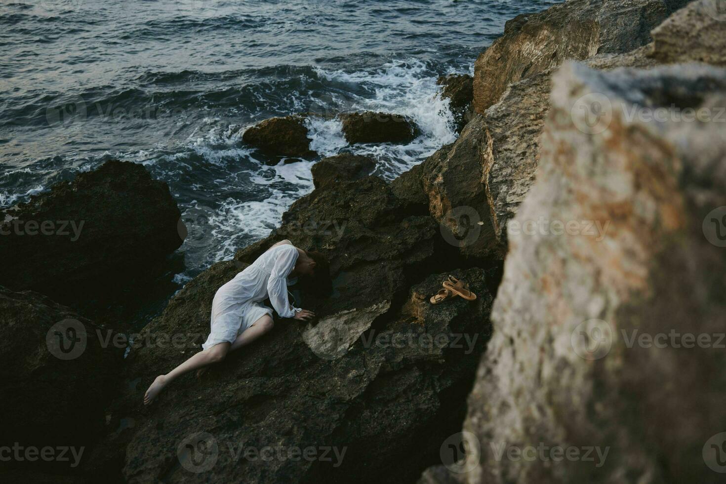 sensual woman lying on her back on a rocky seashore landscape photo