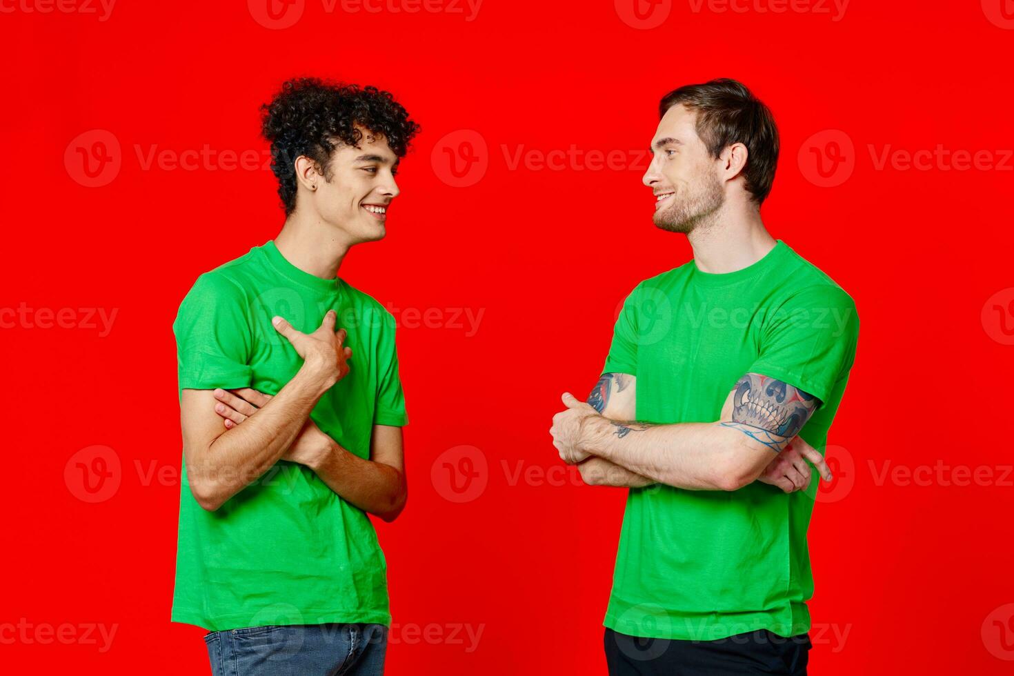 two friends in green t-shirts are standing side by side communication positive red background photo