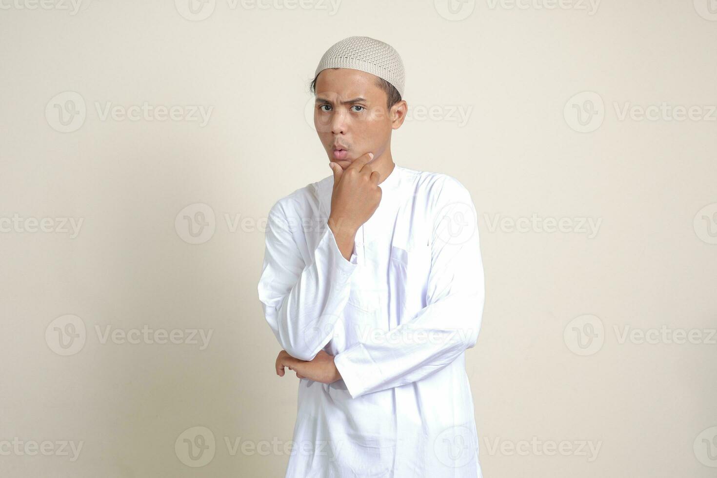 Portrait of attractive Asian muslim man in white shirt thinking about question with hand on chin. Isolated image on gray background photo