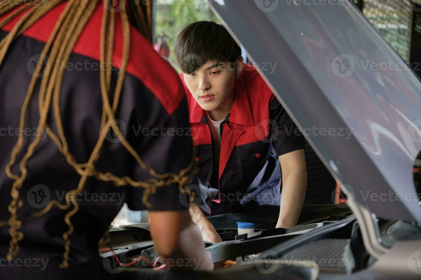 dos profesional automotor mecánico socios cheque y reparar un ev coche batería y híbrido motor a un mantenimiento cochera, experto eléctrico vehículo servicio, y fijación ocupaciones auto industria. foto