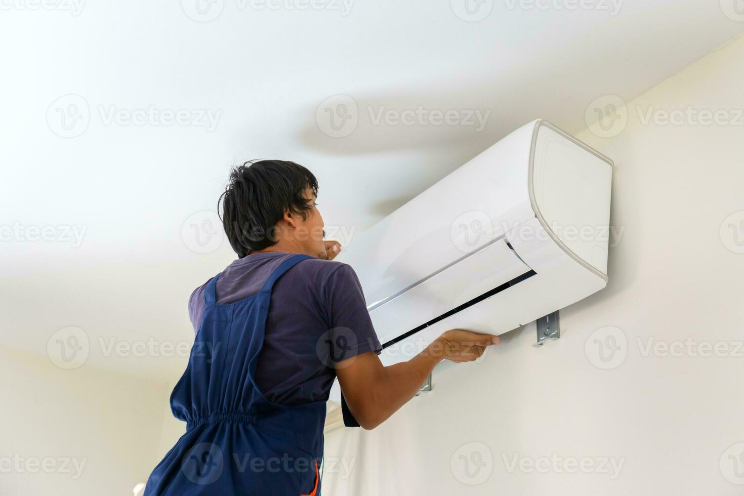 Electrician installing air conditioner unit, Technician man installing an air conditioning in a client house, Repairman fixing air conditioner unit, Maintenance and repairing concepts photo