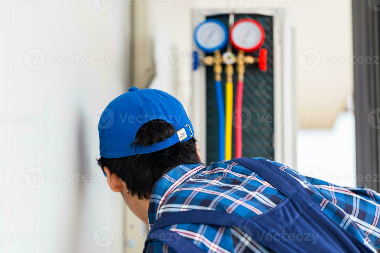 Rear view of repairman fixing air conditioner unit, Technician man