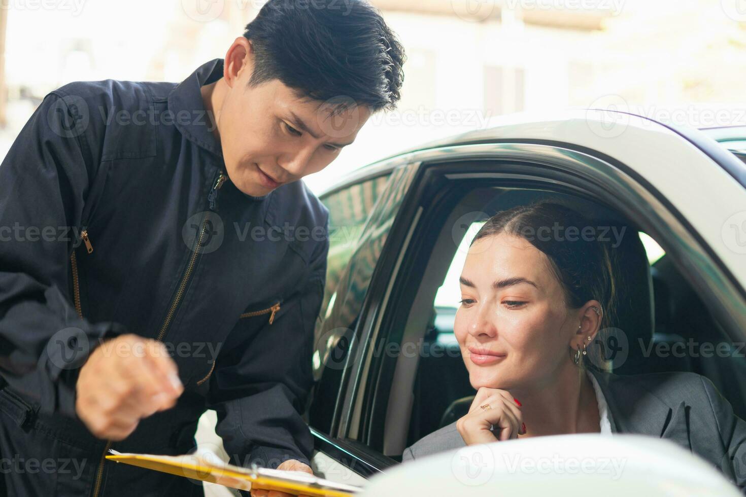 mecánico y cliente hablando juntos a el reparar cochera, auto mecánico y hembra cliente en auto reparar tienda foto