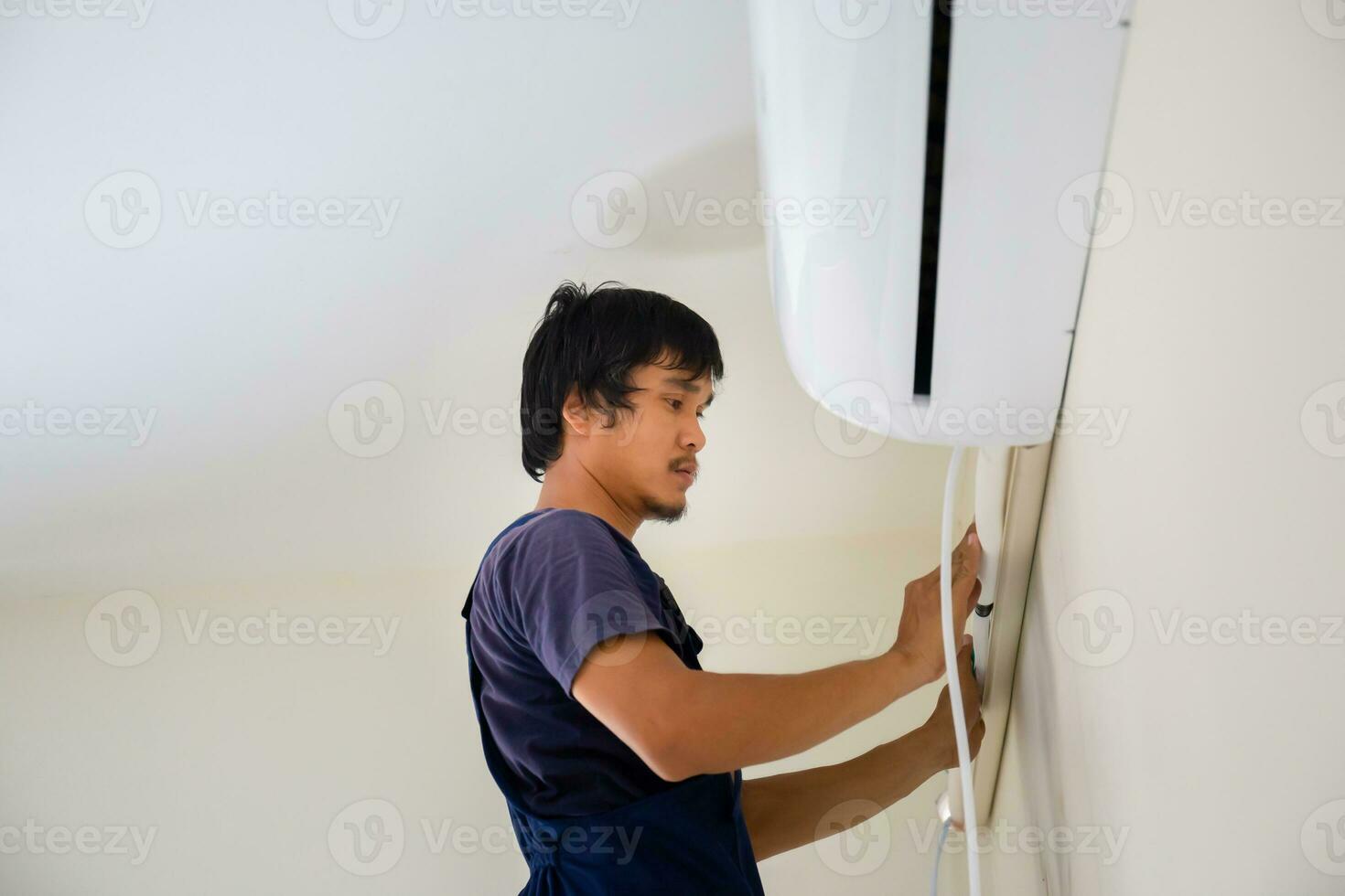Technician man installing air conditioning in a client house, Young repairman fixing air conditioner unit, Maintenance and repairing concepts photo