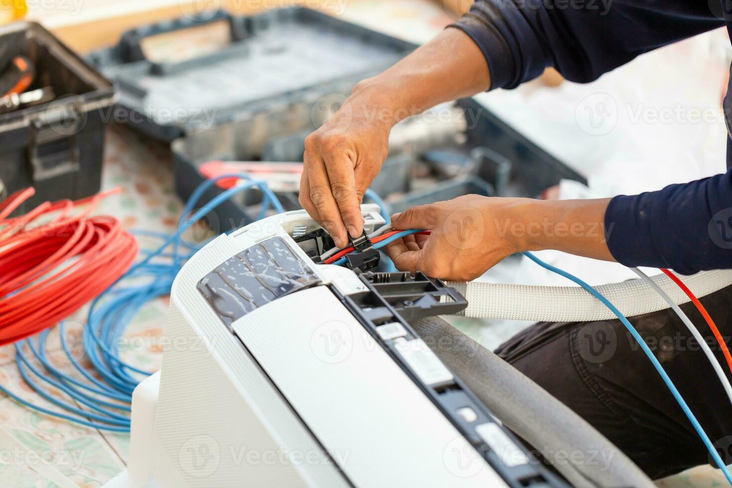 Technician man installing air conditioning in a client house, Electrician mounting the wires into air conditioning unit, Repairman fixing air conditioner unit, Maintenance and repairing concepts photo