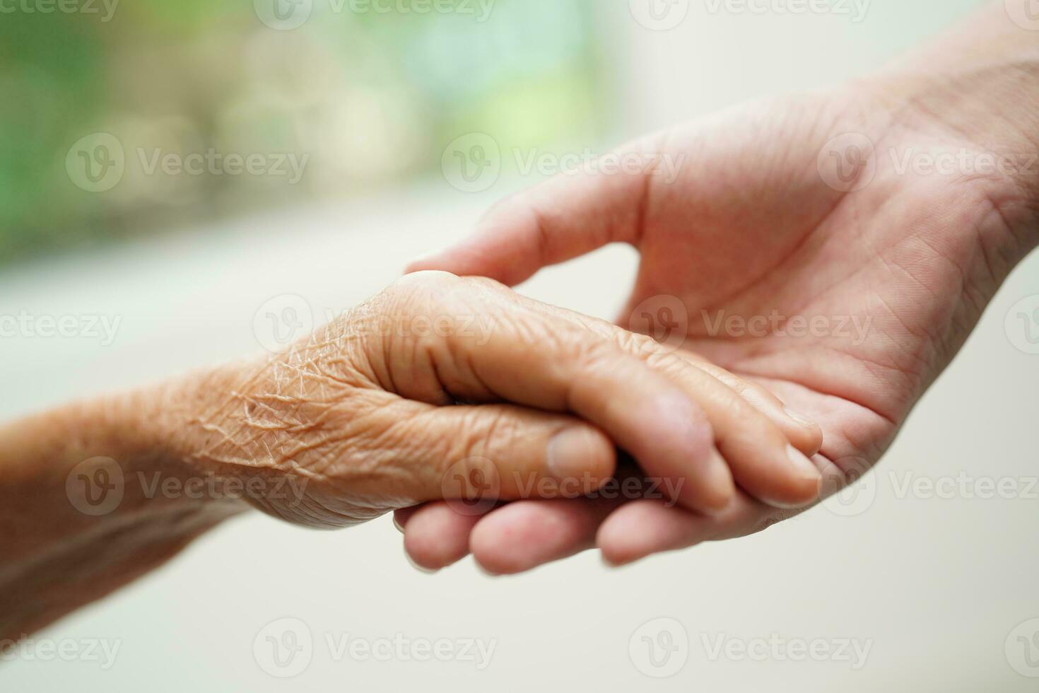 Asian young boy holding old grandmother woman hand together with love and care. photo