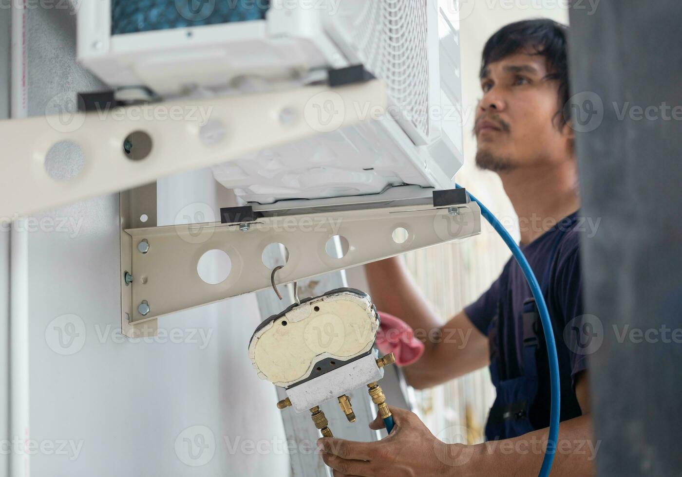 Young repairman fixing air conditioner unit, Asian technician man installing an air conditioning in a client house, Maintenance and repairing concepts photo