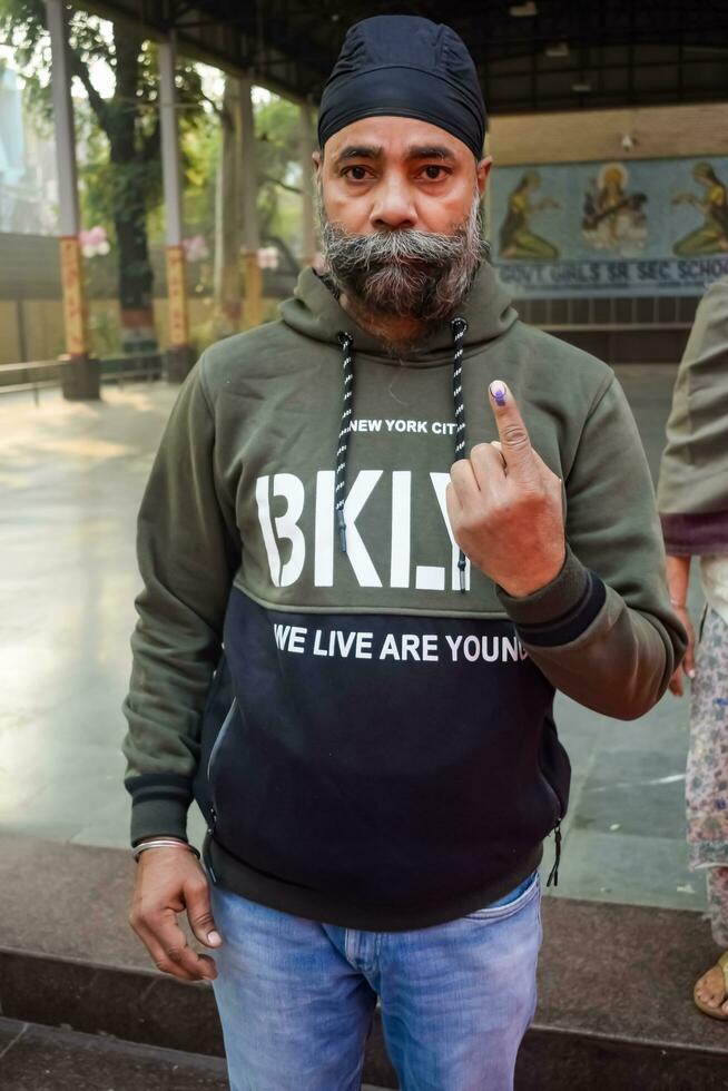 New Delhi, India - March 04 2023 - Unidentified people showing their ink-marked fingers after casting votes in front of polling booth of east Delhi area for MCD local body Elections 2022 photo